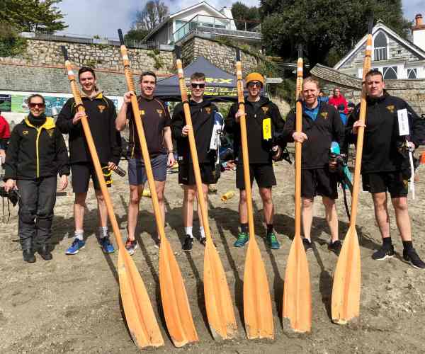 Mens A crew stood in a line with their oars resting on their shoulders